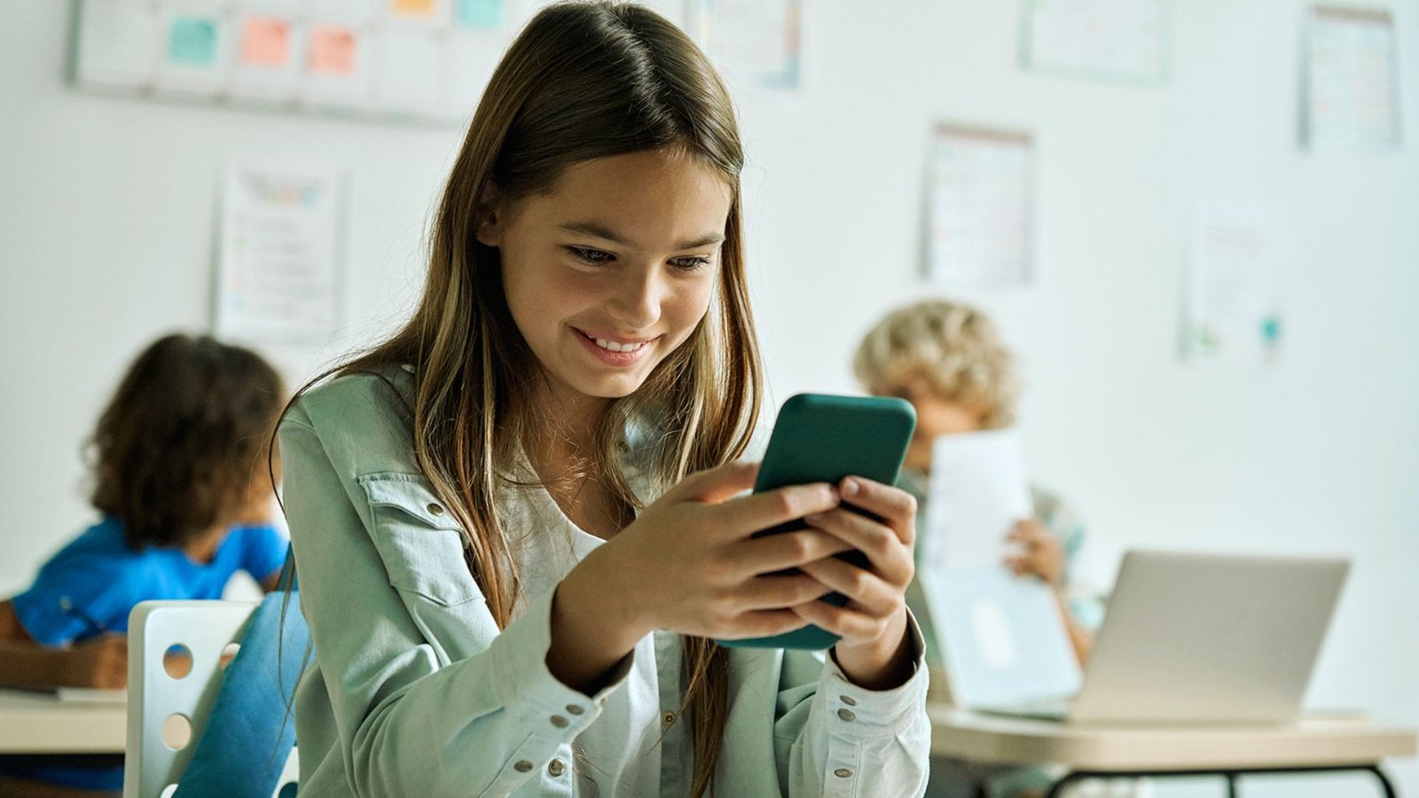 A girl smiles while using her phone, enjoying a moment of connection and happiness.