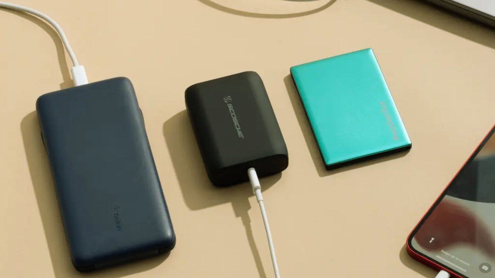 A power bank, laptop, and smartphone arranged together on a surface, showcasing portable charging options.
