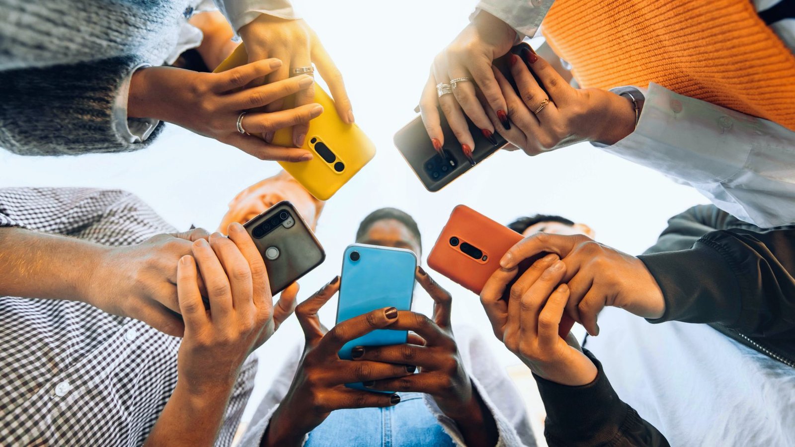 A diverse group of people enthusiastically holding up their cell phones, capturing a moment together.
