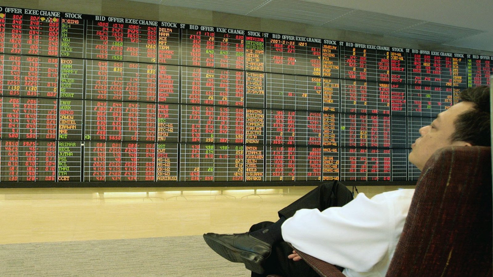A man seated in front of a large screen, focused on the display.
