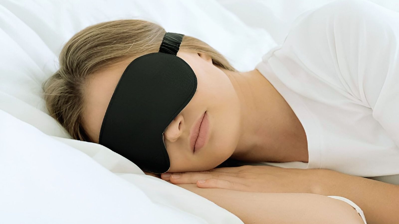 A woman peacefully sleeping while wearing a black eye mask to block out light.