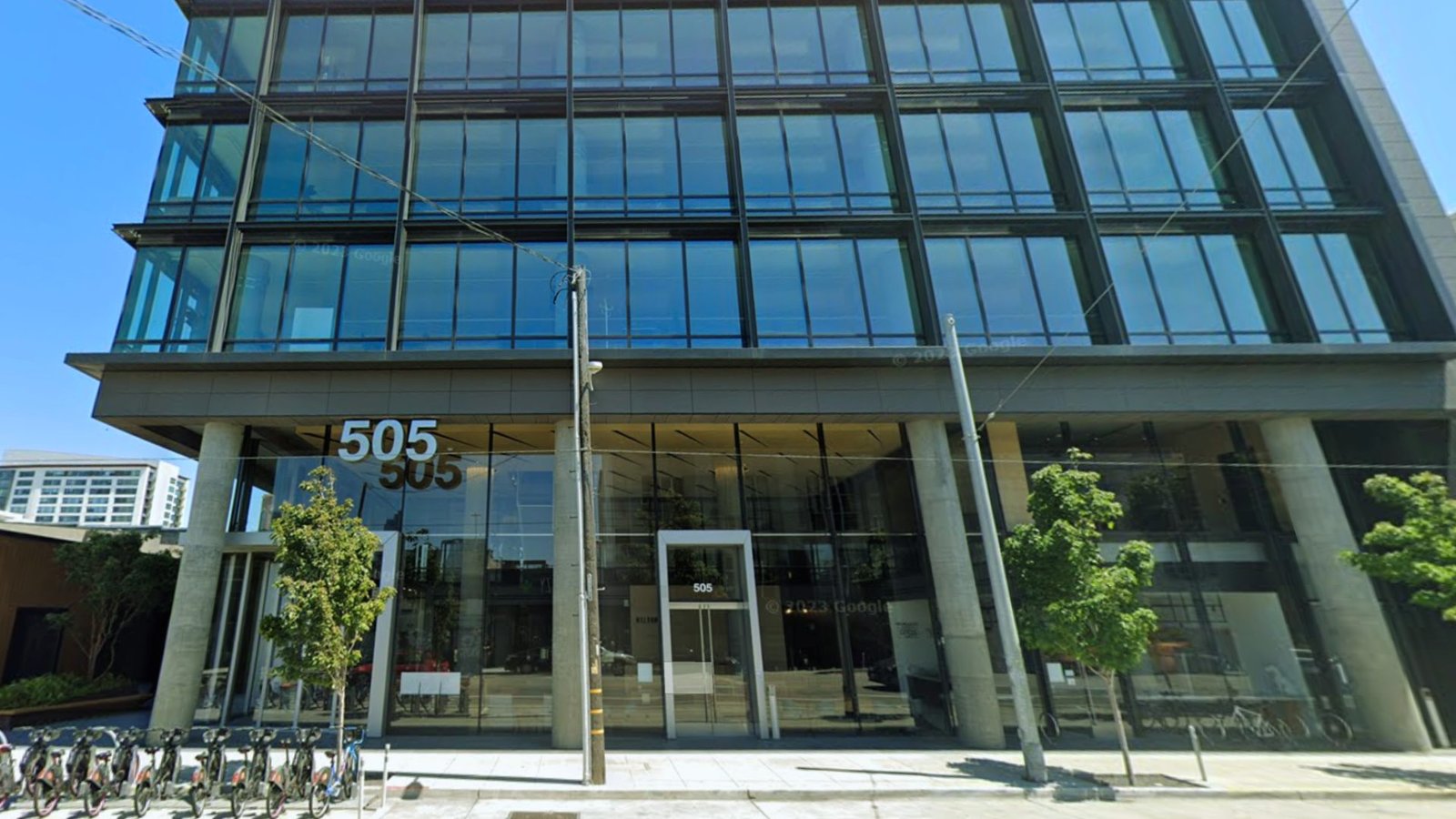 A large building featuring a prominent glass window that reflects the surrounding environment.
