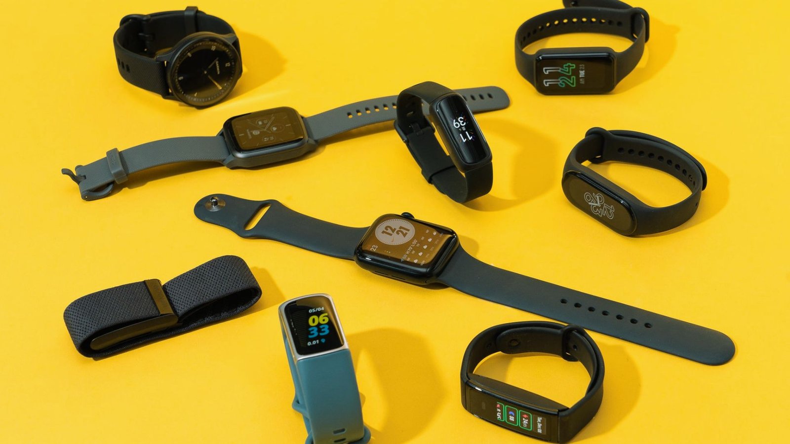  A collection of smart watches displayed on a bright yellow surface, showcasing various designs and features.