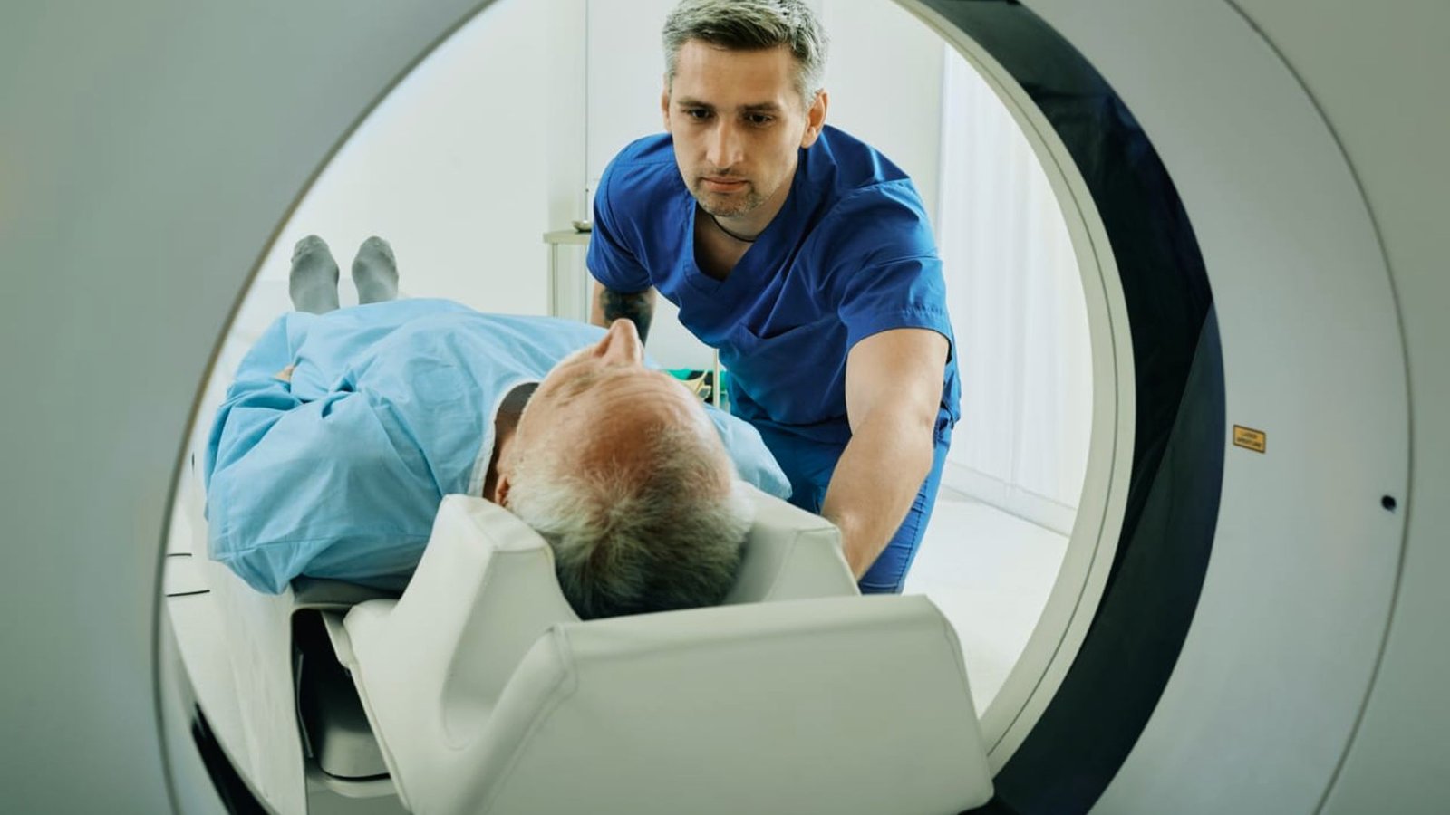 A man lies inside an MRI machine while a doctor examines him.