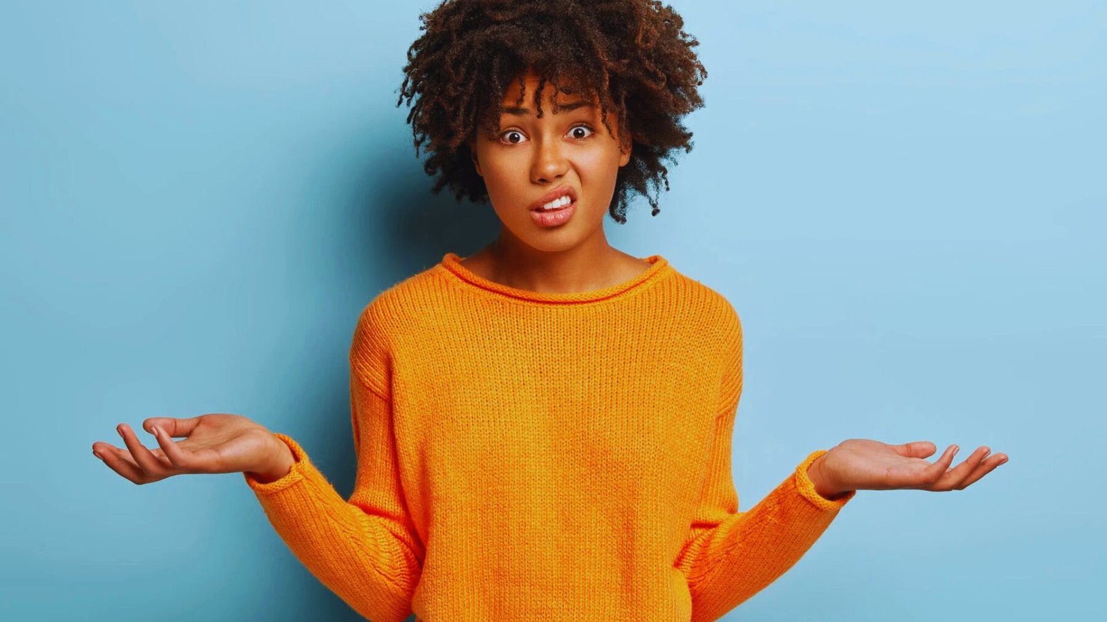 A woman with an open hand gestures expressively, conveying emotion on her face.
