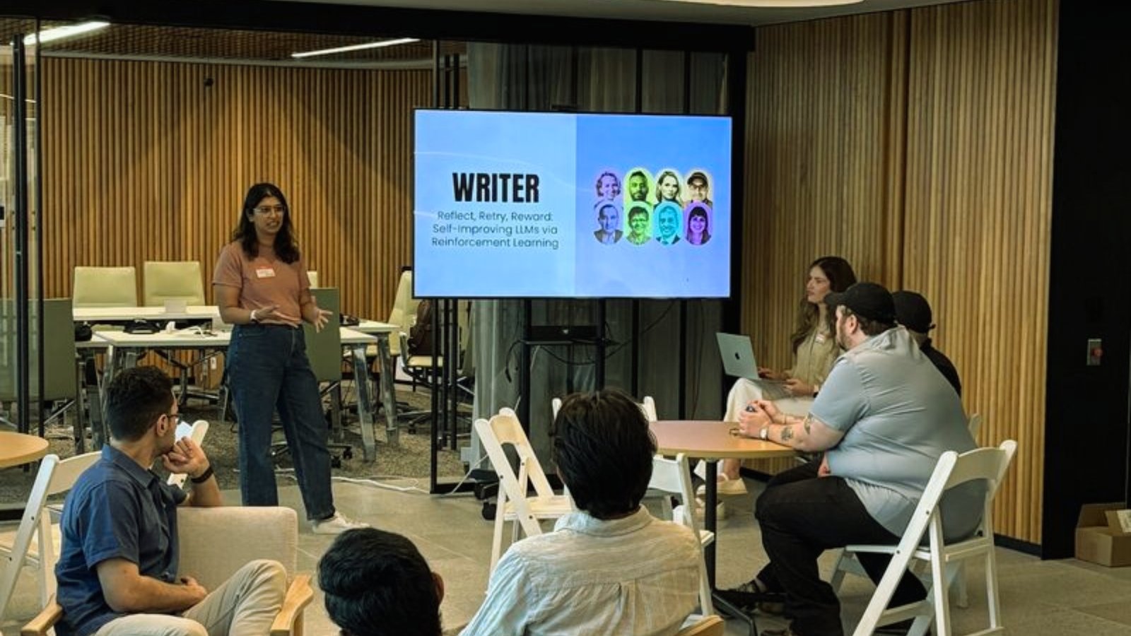 A group of people engaged in discussion while sitting around tables in a modern office setting.