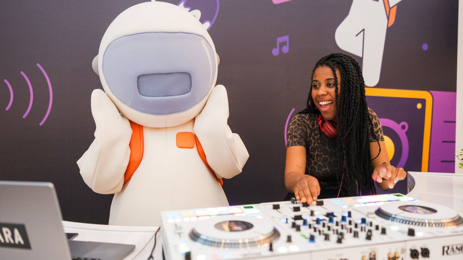 A woman plays music alongside a DJ, with a robot standing in front of them, creating a lively performance atmosphere.