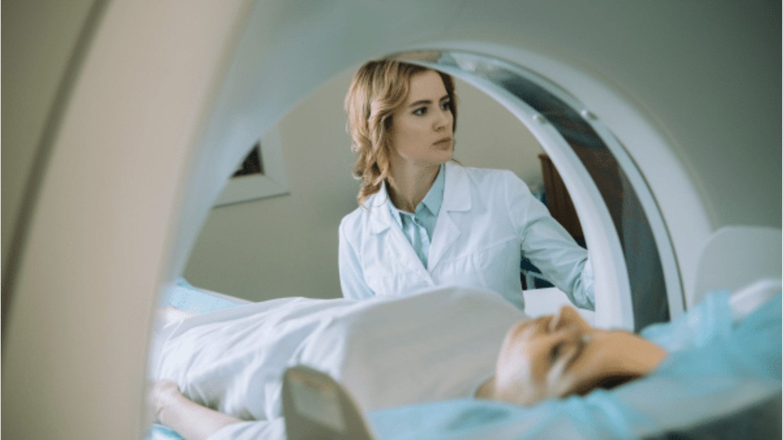  A woman in a white coat examines an MRI machine in a medical setting, showcasing her professional engagement with the equipment.