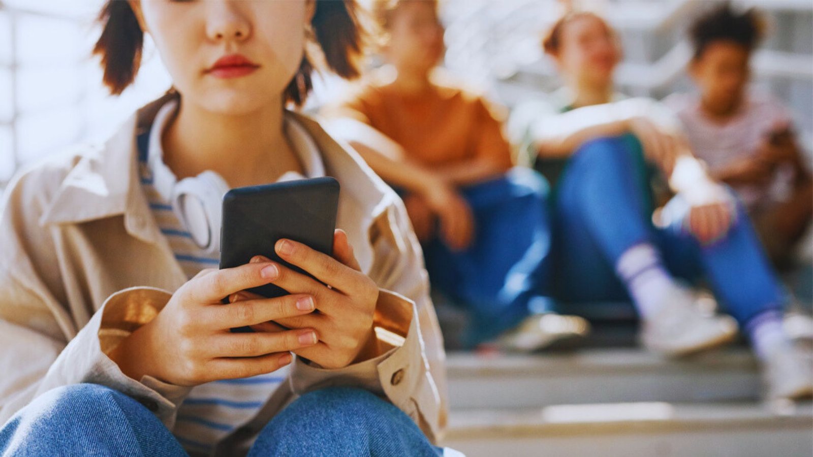 A girl sitting on outdoor steps, focused on her phone, with a casual and relaxed posture.