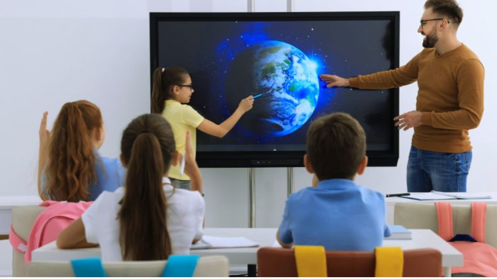 A teacher explains Earth’s features to a group of attentive children in a classroom setting.
