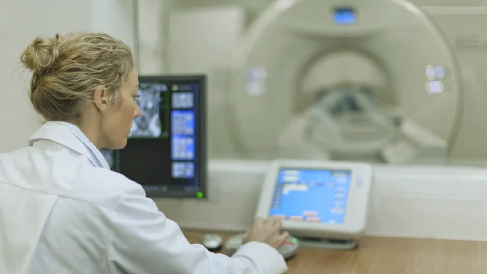  A woman in a white lab coat examines data on a computer screen in a laboratory setting.
