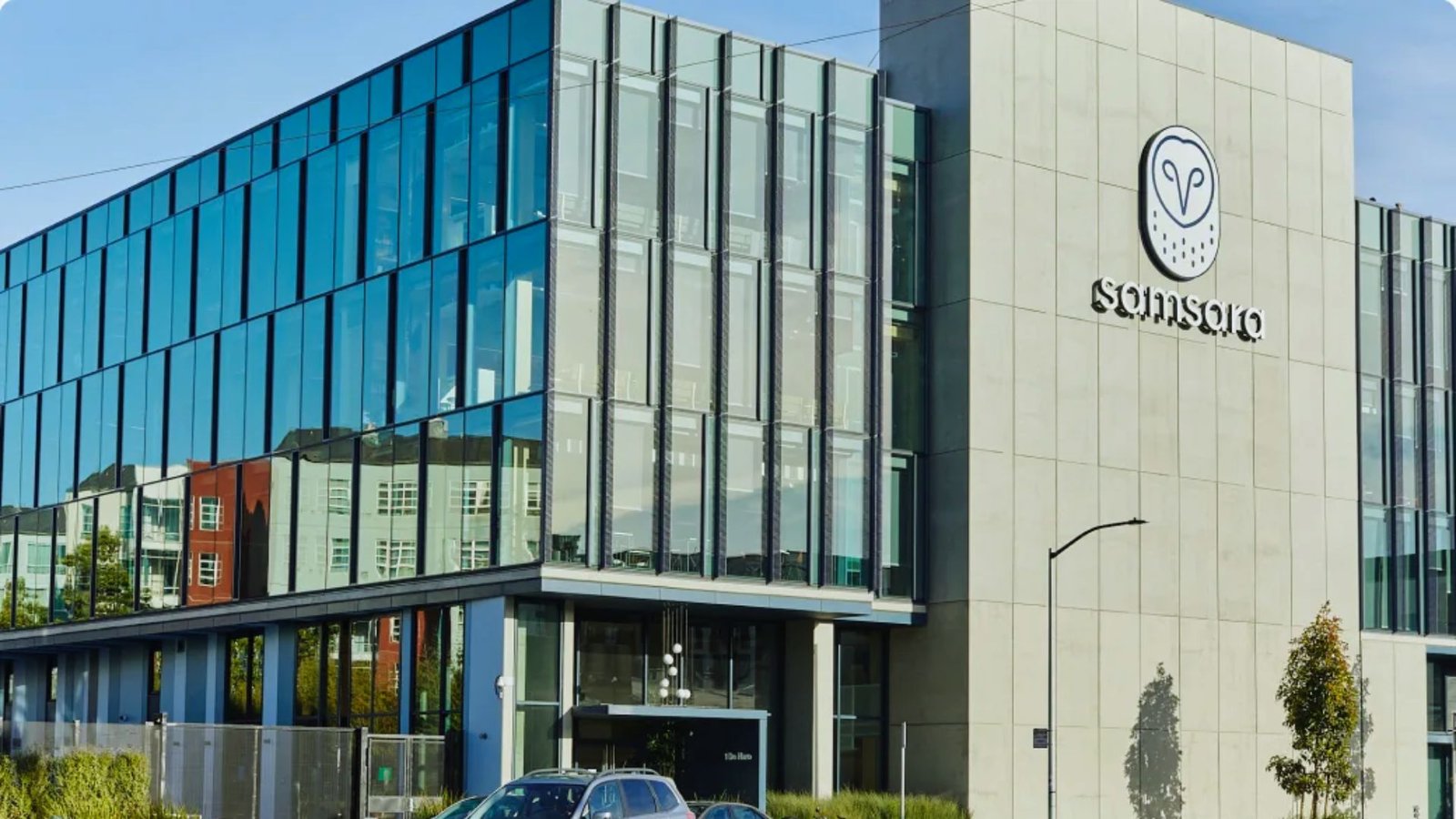  A modern glass building featuring a prominent large sign at the front, reflecting its contemporary architectural design.