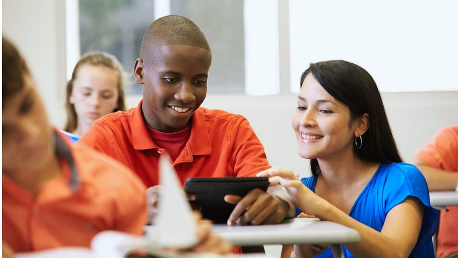 A young boy and girl are intently looking at a tablet together, sharing an engaging moment of discovery.