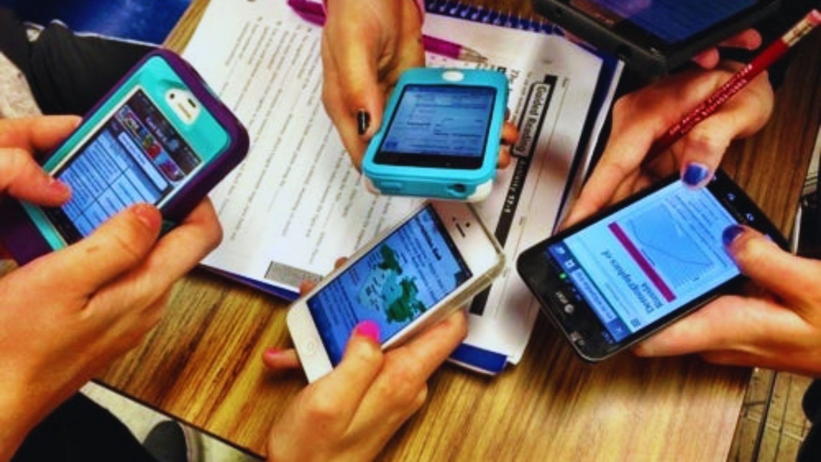 Several individuals gathered, all holding their cell phones and engaging with the devices in a social setting.
