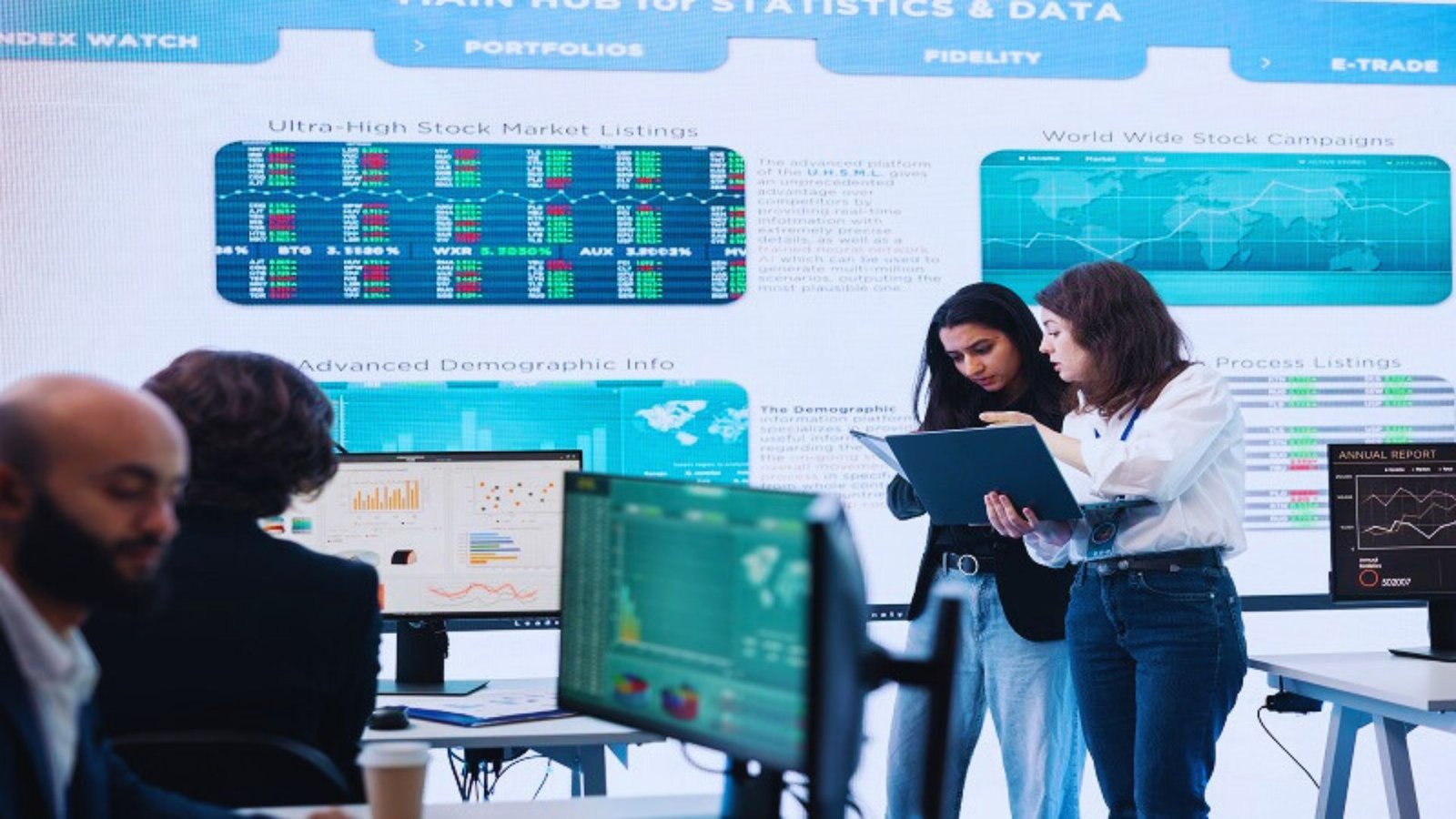 A group of people analyzing a computer screen displaying various statistics and data charts.
