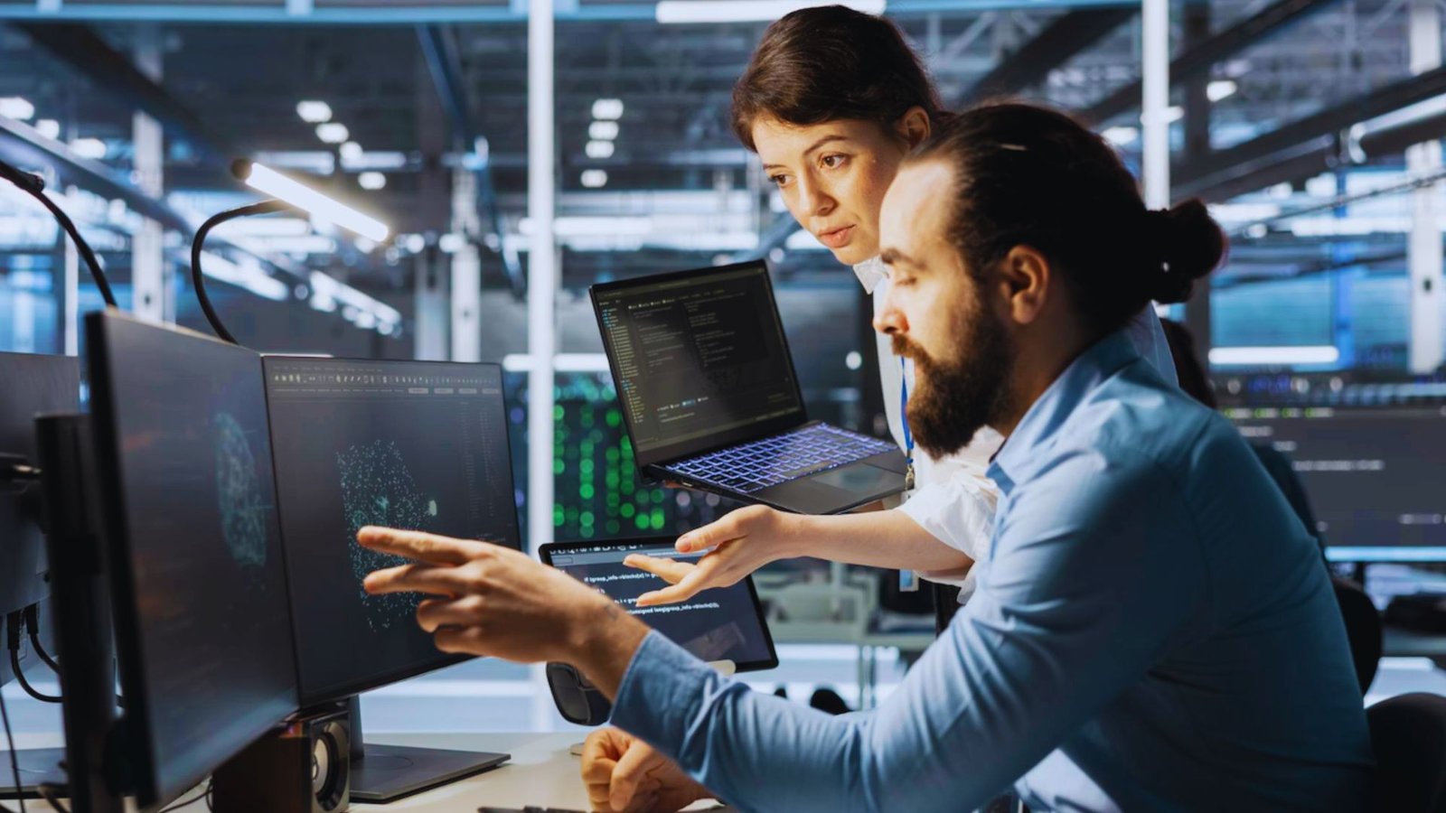 Two colleagues collaborating on a computer in a modern office setting.