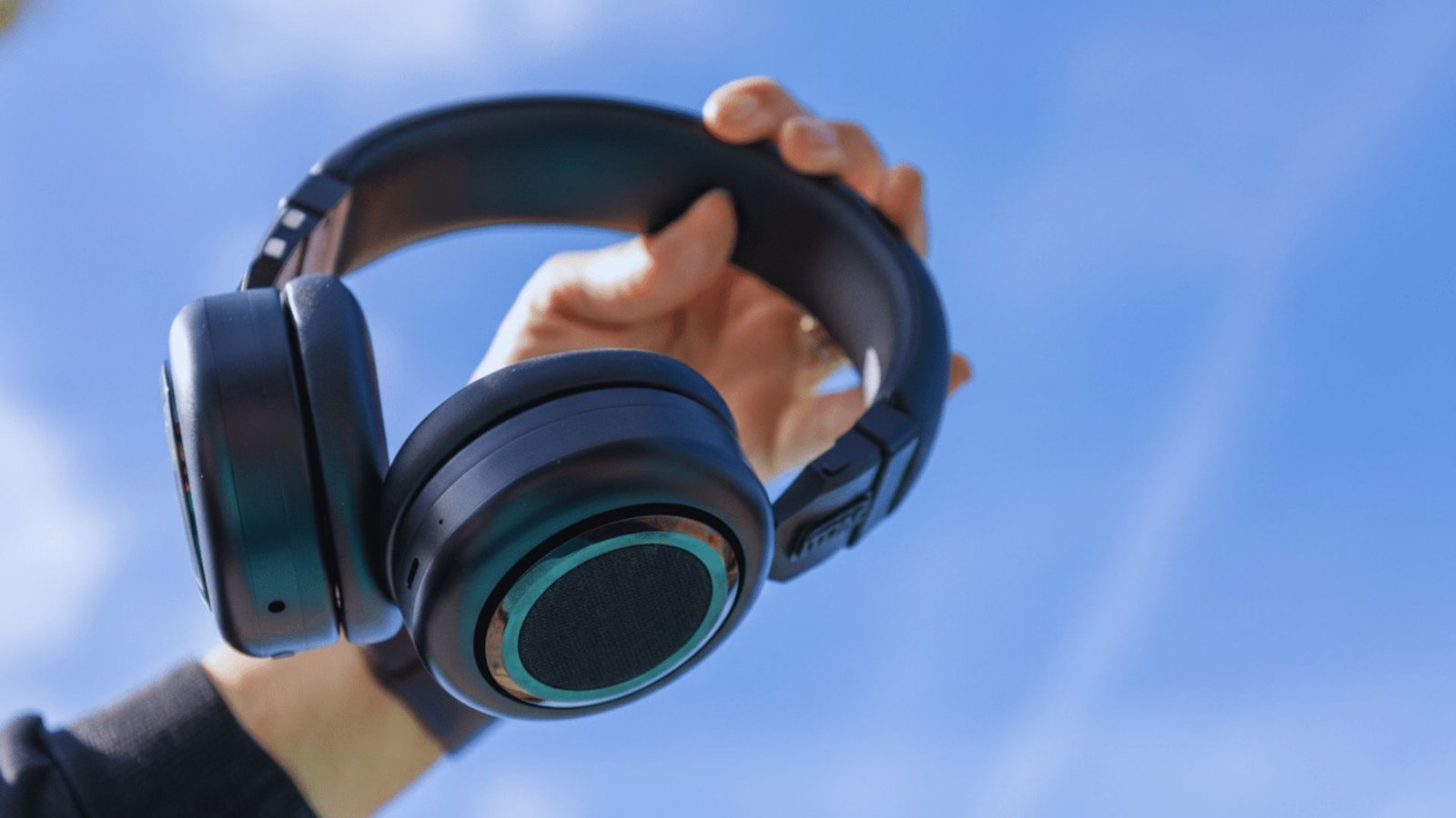 A person holding a pair of headphones up to eye level, showcasing the design and features of the headphones.