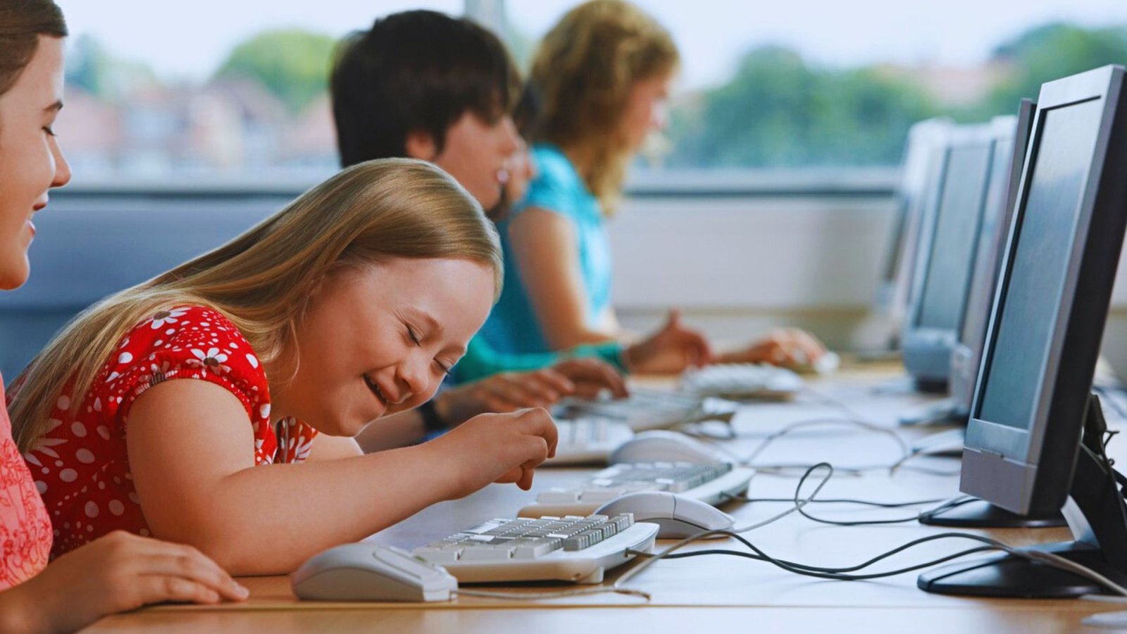  Children engaged in playing computer games together in a classroom setting, focused on their screens and enjoying the activity.