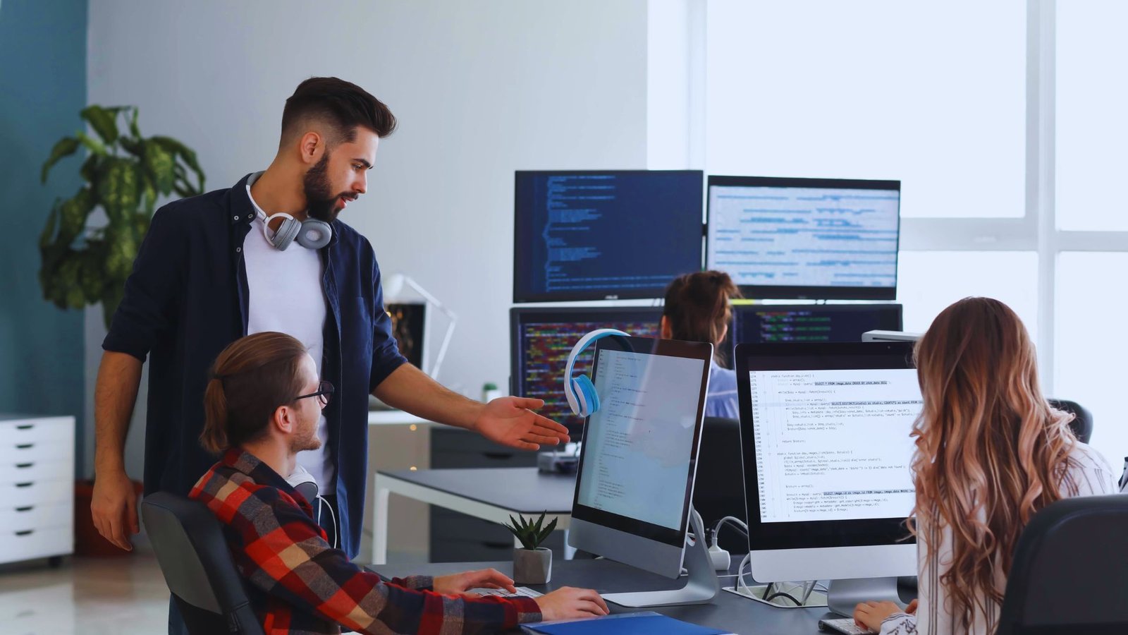  A man stands before a group of people focused on their computers in a collaborative workspace.