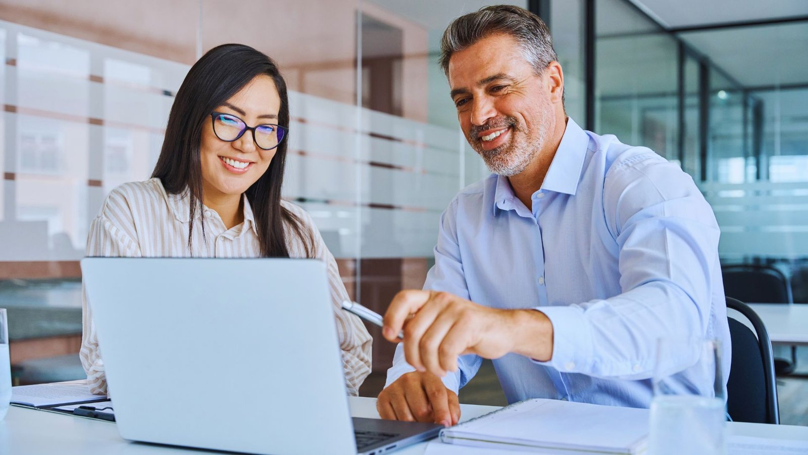 A man and woman smile at a laptop, sharing a moment of joy and collaboration.