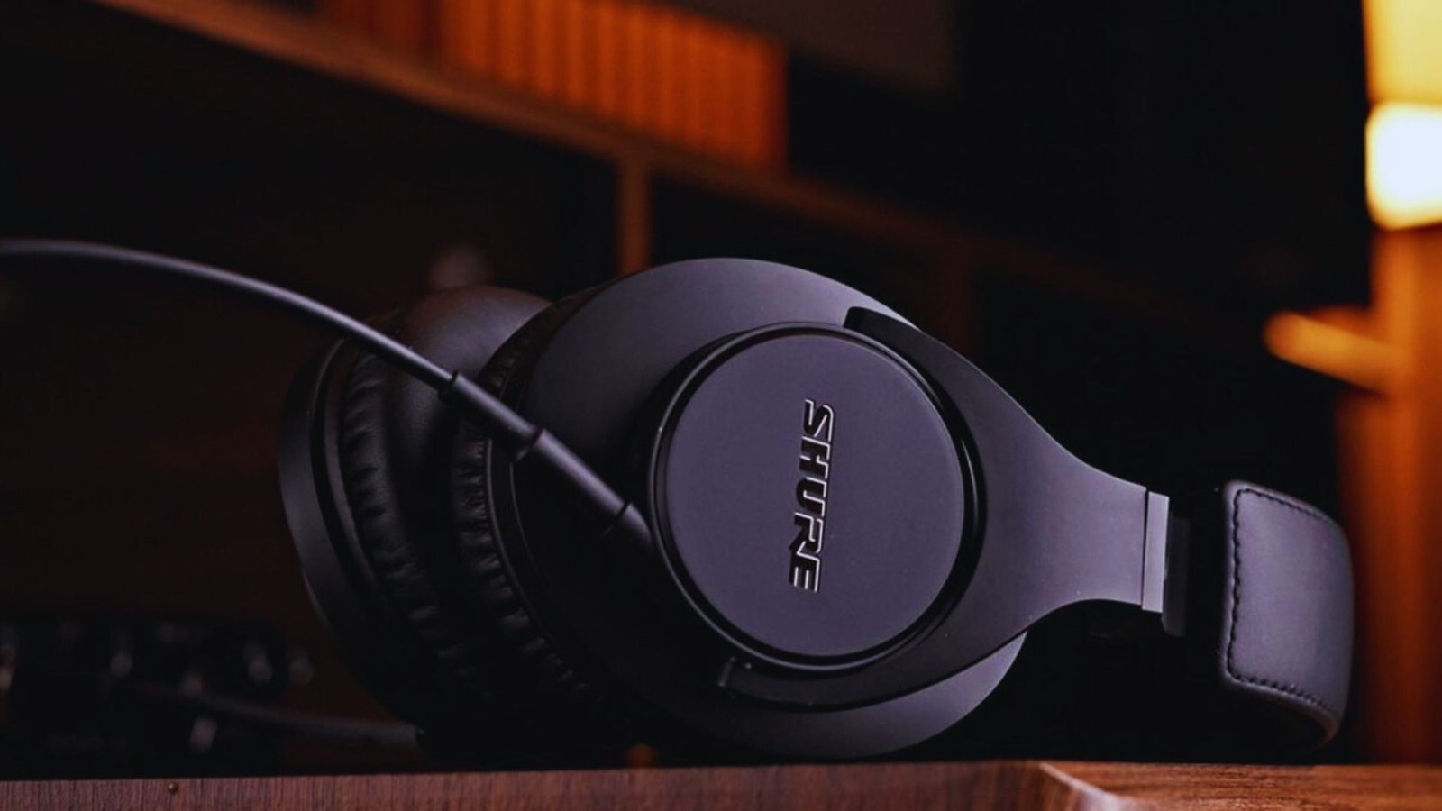  A pair of headphones resting on a desk in a well-lit room, surrounded by a calm and organized atmosphere.