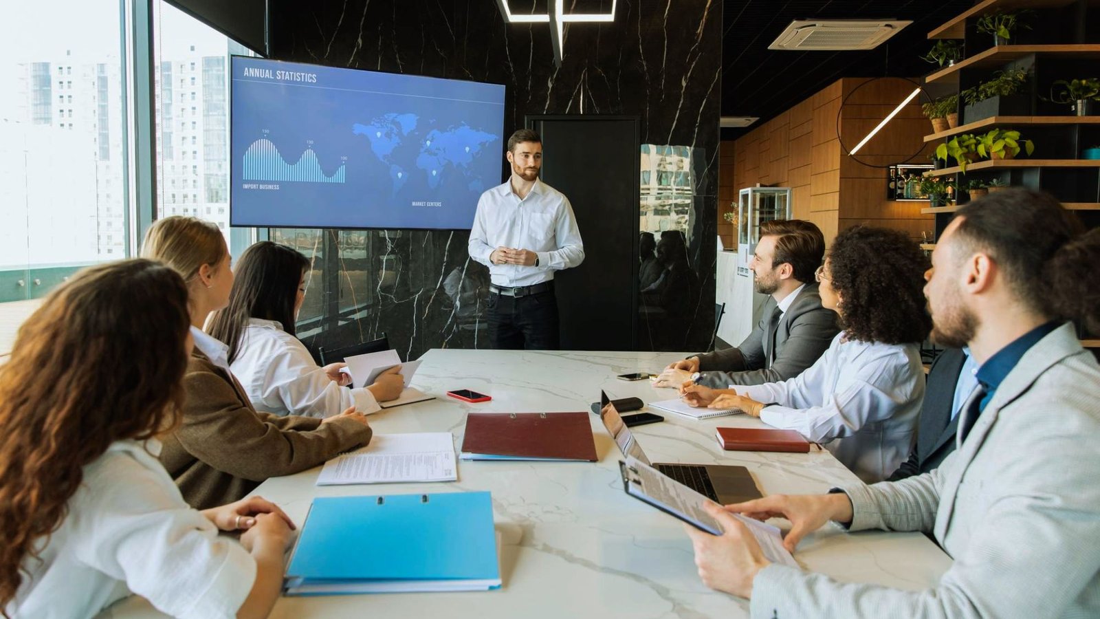 A man presenting to an audience, engaging with a group of attentive listeners in a conference setting.