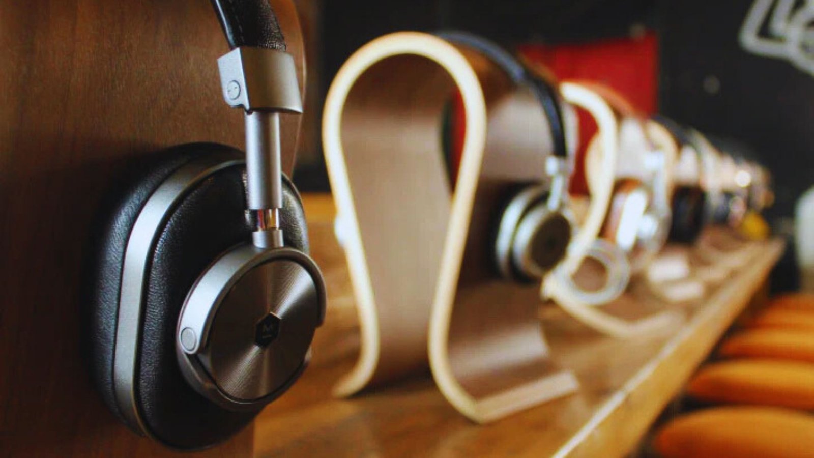 A row of various headphones neatly arranged on a wooden shelf.