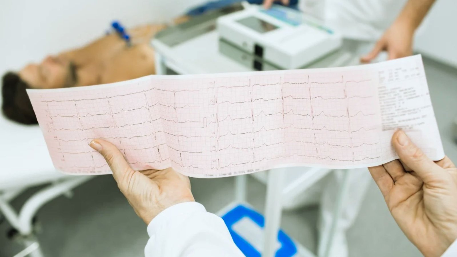 A person holds an ECG paper in front of another person, displaying heart rhythm data for medical assessment.