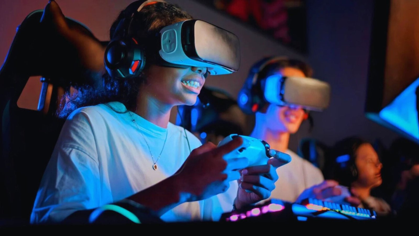  A woman in virtual reality goggles engages with a virtual world as a man plays video games on a screen beside her.