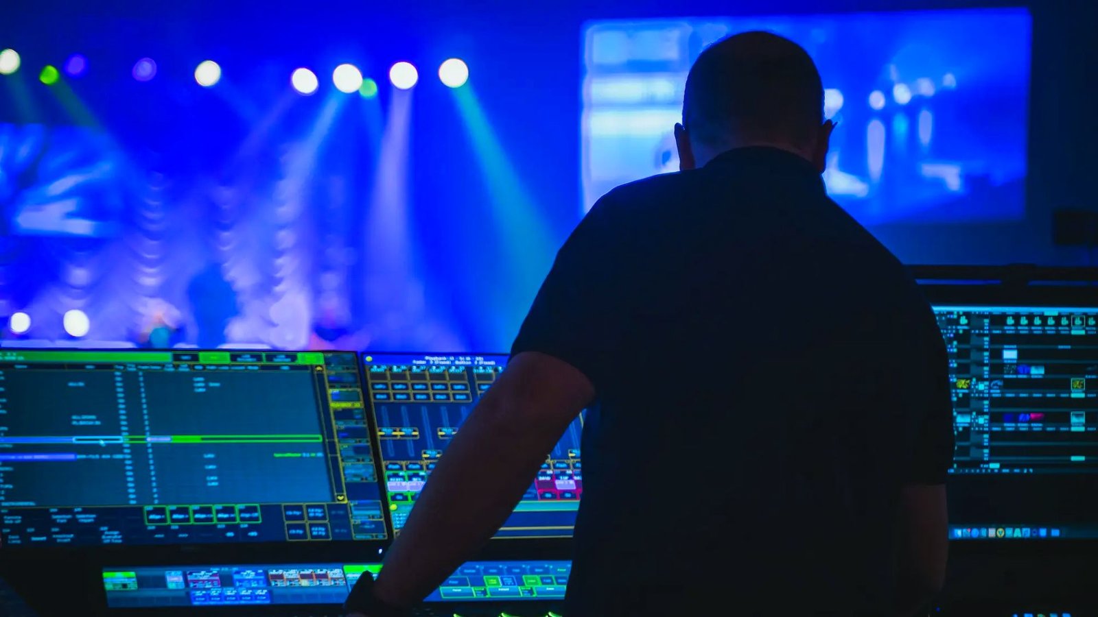 A man in a black shirt stands in front of a stage, ready for a performance or presentation.