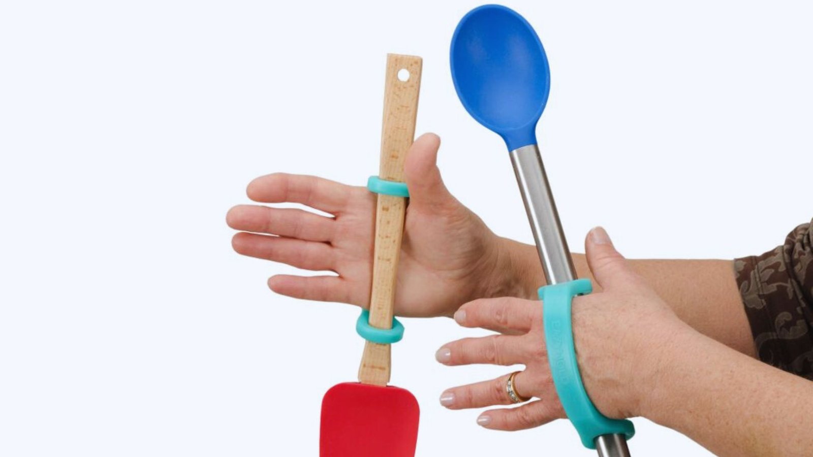  A person holding two spoons in one hand and a single spoon in the other hand, showcasing a playful kitchen moment.