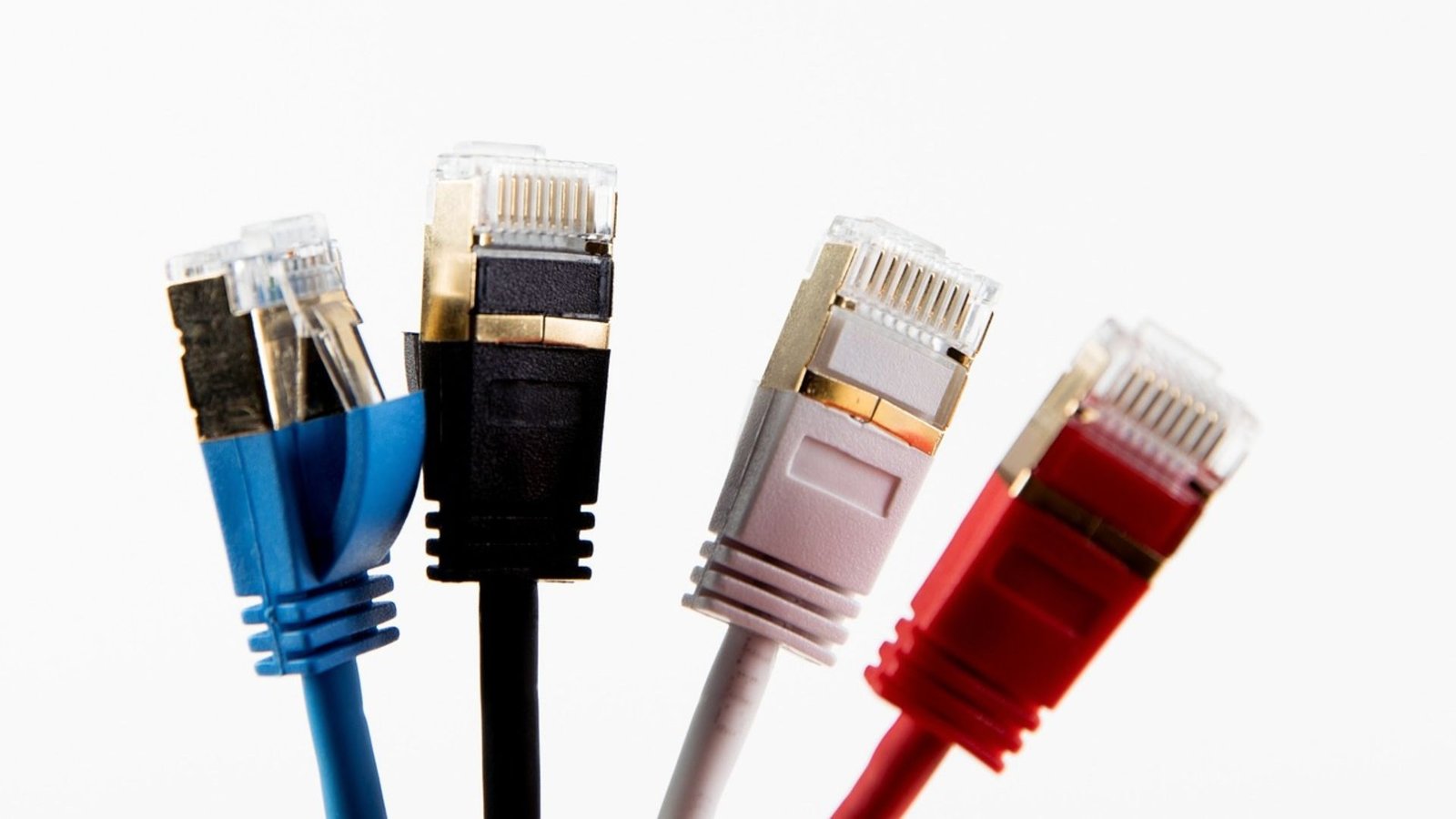 Five Ethernet cables in blue, black, grey, white, and red with transparent connectors are lined up against a white background.