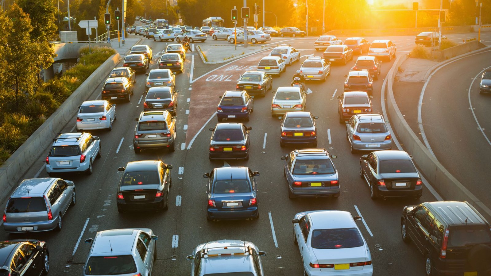 Heavy urban traffic jam at sunset with congested lanes filled with various cars. The warm sunlight casts a golden hue, creating a tense yet serene atmosphere.