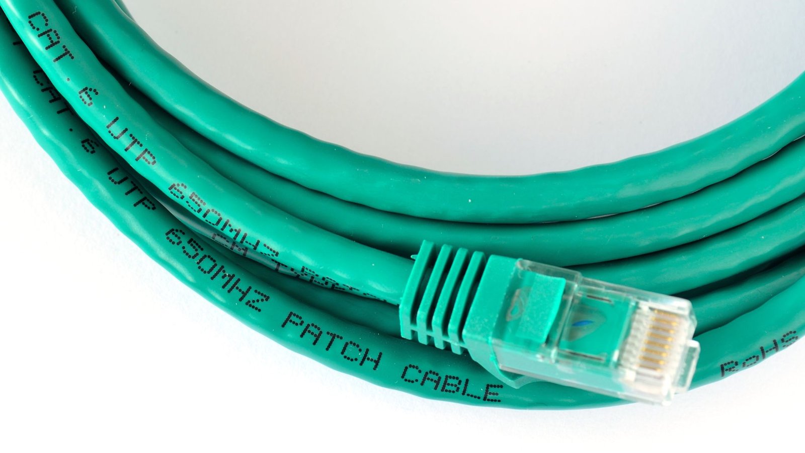 Coiled green Ethernet Cat 6 cable with visible connector. Black text on cable reads "650MHz Patch Cable" indicating high-speed data use.